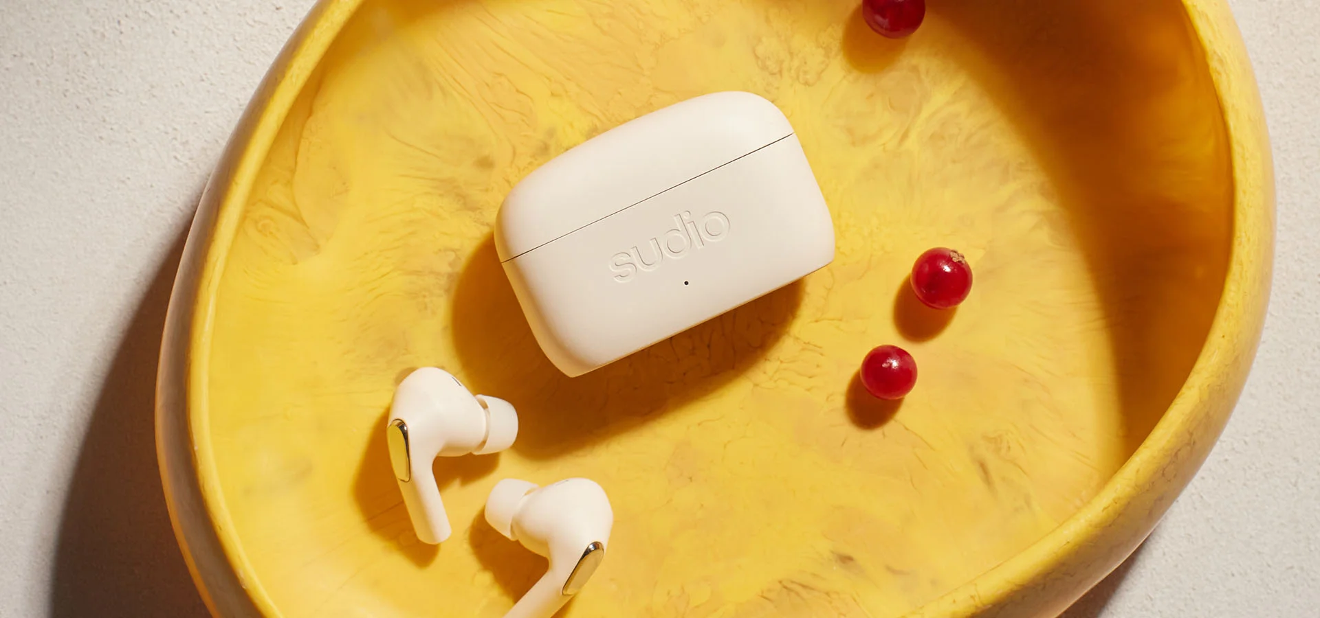 Sudio E3 Cream White earbuds on a plate