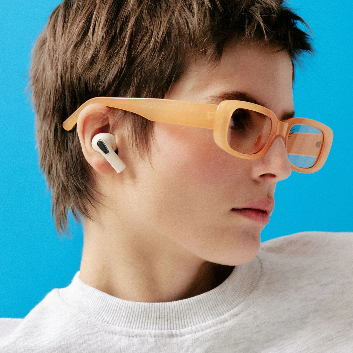 Sudio E3 Cream White earbuds on a female model with a paor of sunglasses